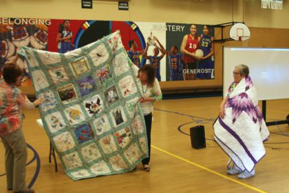 Mary Jane is presented with a quilt that includes squares designed by students and staff