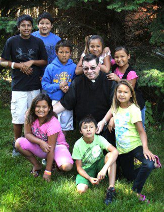 Fr. Anthony Kluckman, chaplain at St. Joseph's Indian School, with some of the many children helped by the work of the new Donor Care Center