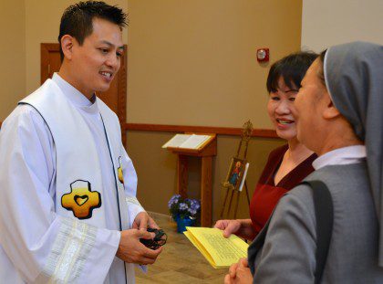 Fr. Joseph Dinh, associate pastor at St. Martin of Tours, with visitors at the feast-day Mass.