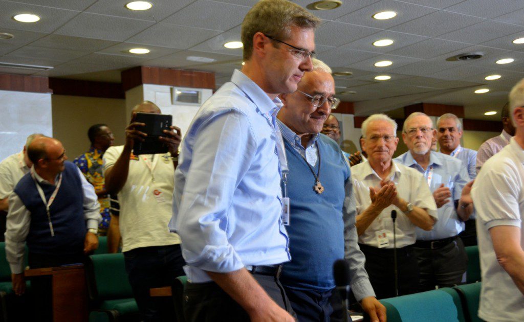 Fr. Ornelas, the out-going general superior, brings his successor to the front of the meeting room. 