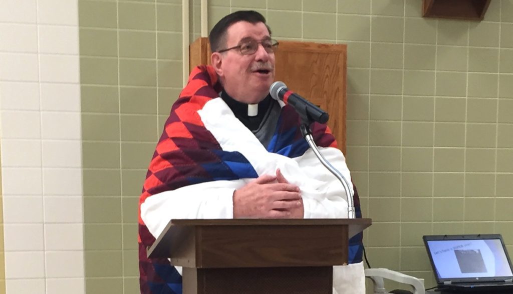 Fr. Anthony draped in the star quilt given to him by the staff of St. Joseph's Indian School.